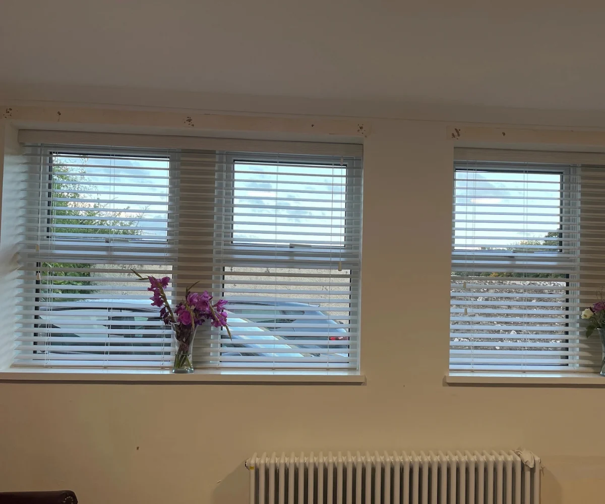 White made-to-measure Venetian blinds professionally fitted across multiple windows in an Airdrie home.